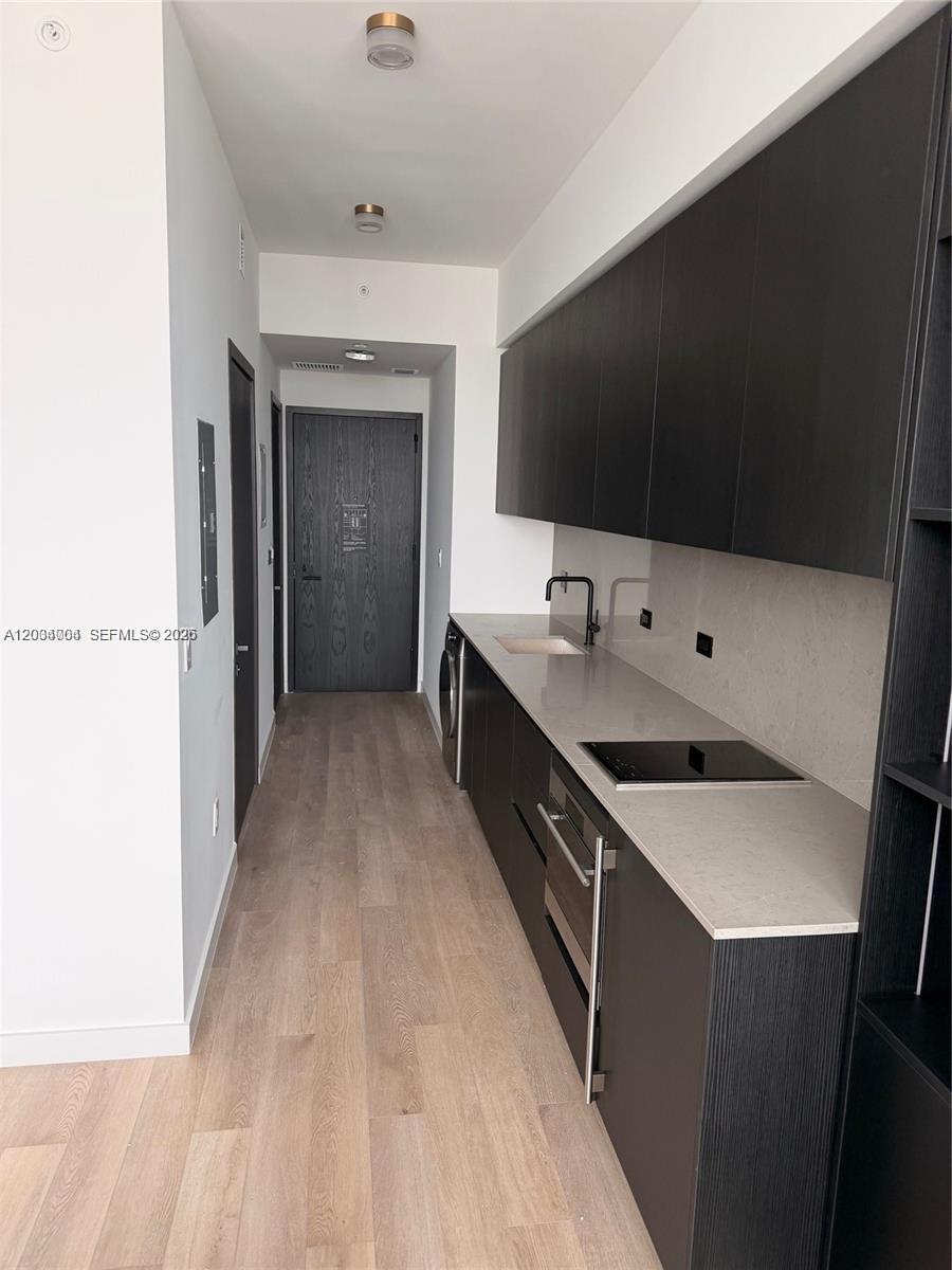 A narrow kitchen features dark cabinetry, light countertops, and light wood-look flooring — 20 NE 11th St # 3703A, Miami FL 33132, MIAMI, FL