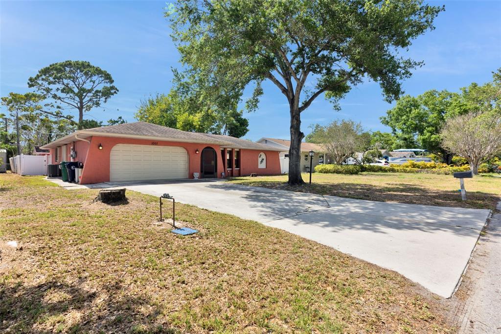 A single-story house with a coral-colored exterior, arched entryway, and a screen-enclosed porch — 1007 22ND AVENUE W, PALMETTO, FL