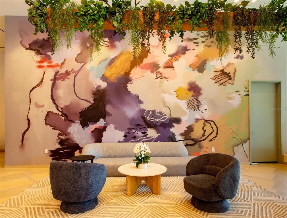 A lounge area features a large abstract mural, a gray sofa, and two dark armchairs — 400 CENTRAL AVENUE UNIT 2001, ST PETERSBURG, FL