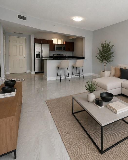 An open-concept living room features a kitchen with a breakfast bar and light-colored flooring — 7270 SW 88th St # B202, Miami FL 33156, MIAMI, FL