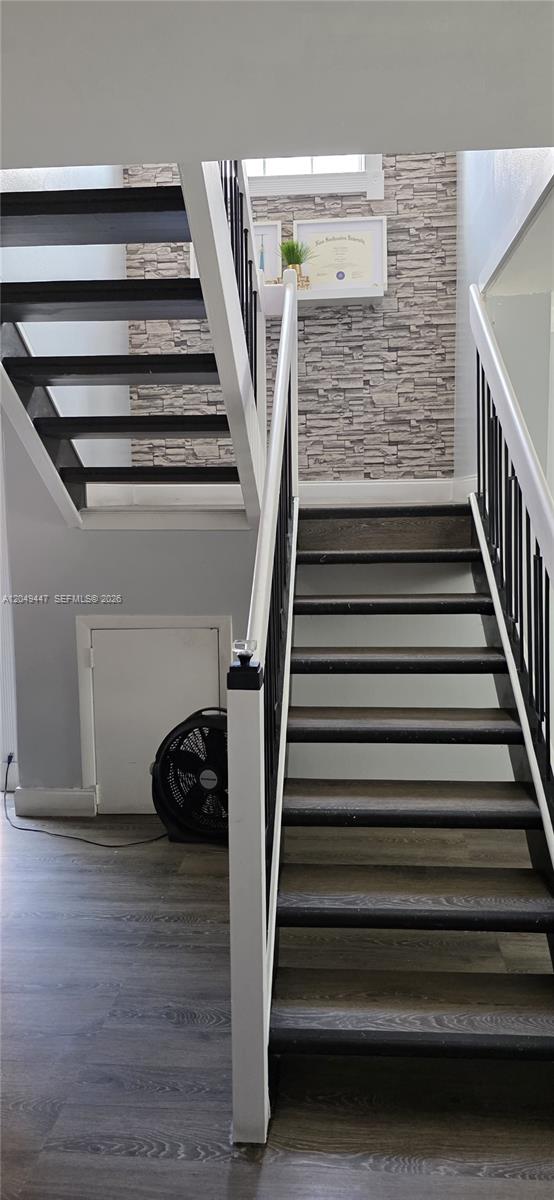 A staircase with dark wooden treads and white railings leads upward against a stone-patterned wall — 3330 Kapot Ter, Miramar FL 33025, MIRAMAR, FL