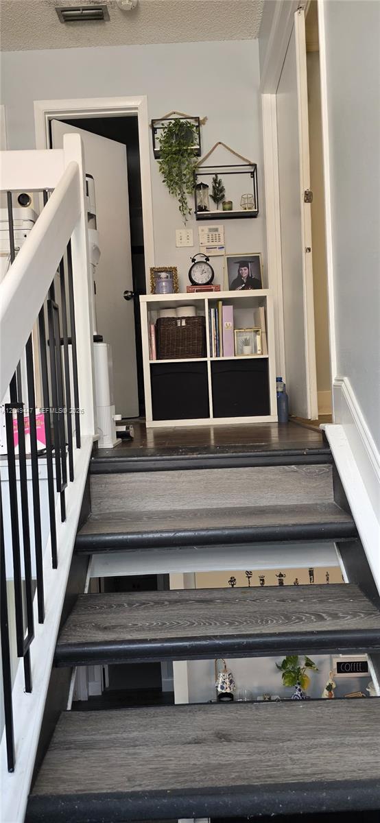 A staircase with dark wood treads leads to a landing featuring a white cube storage unit — 3330 Kapot Ter, Miramar FL 33025, MIRAMAR, FL