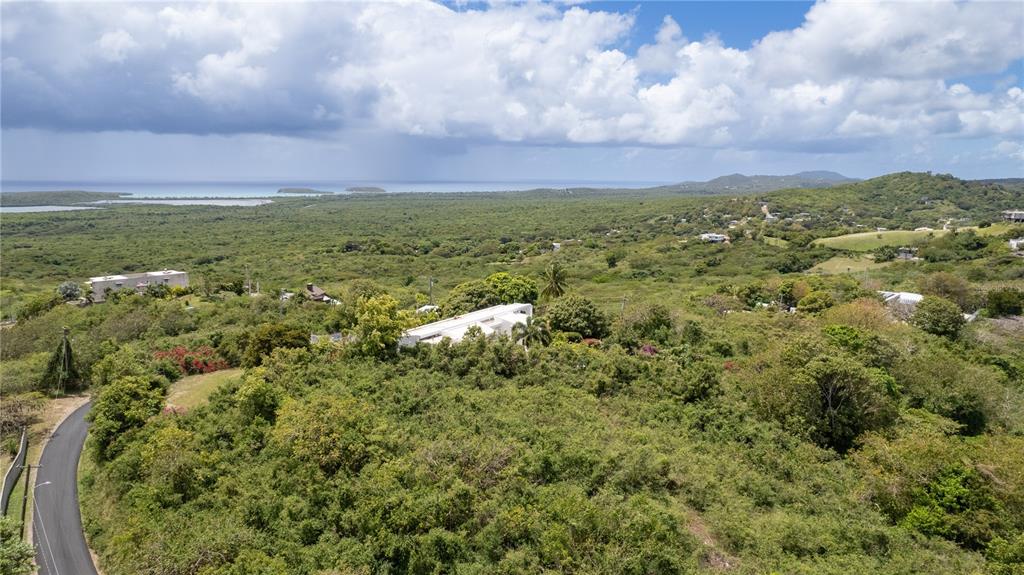 An aerial view shows a white house nestled in a lush, hilly landscape near water — 18 CALLE 16, VIEQUES, PR