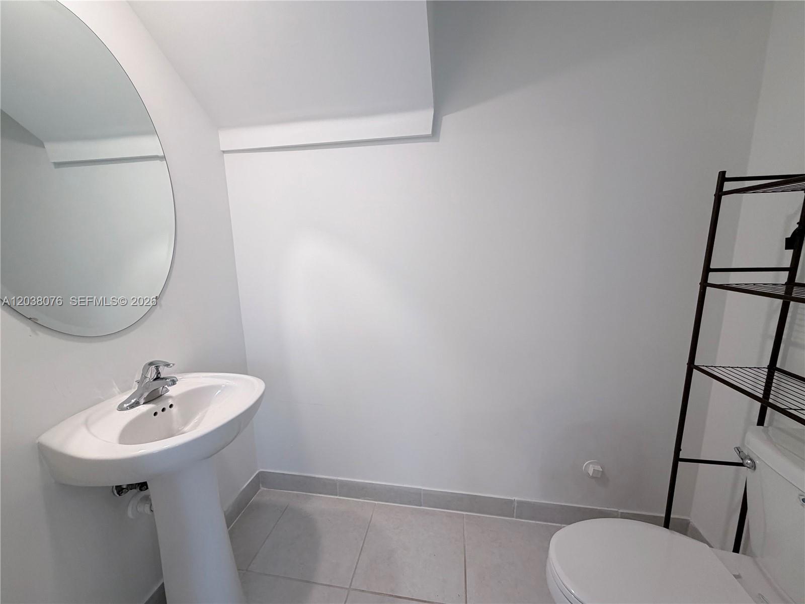 A bathroom features a pedestal sink, a round mirror, a toilet, and a metal shelf — 13421 SW 287th Ter, Homestead FL 33033, HOMESTEAD, FL
