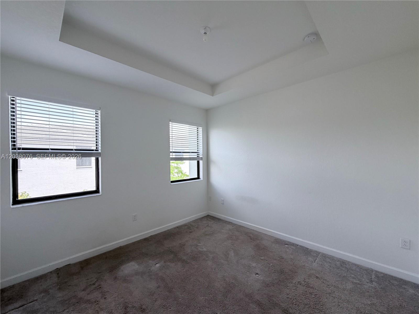 An empty bedroom features white walls, gray carpeting, two windows with blinds, and a tray ceiling — 13421 SW 287th Ter, Homestead FL 33033, HOMESTEAD, FL