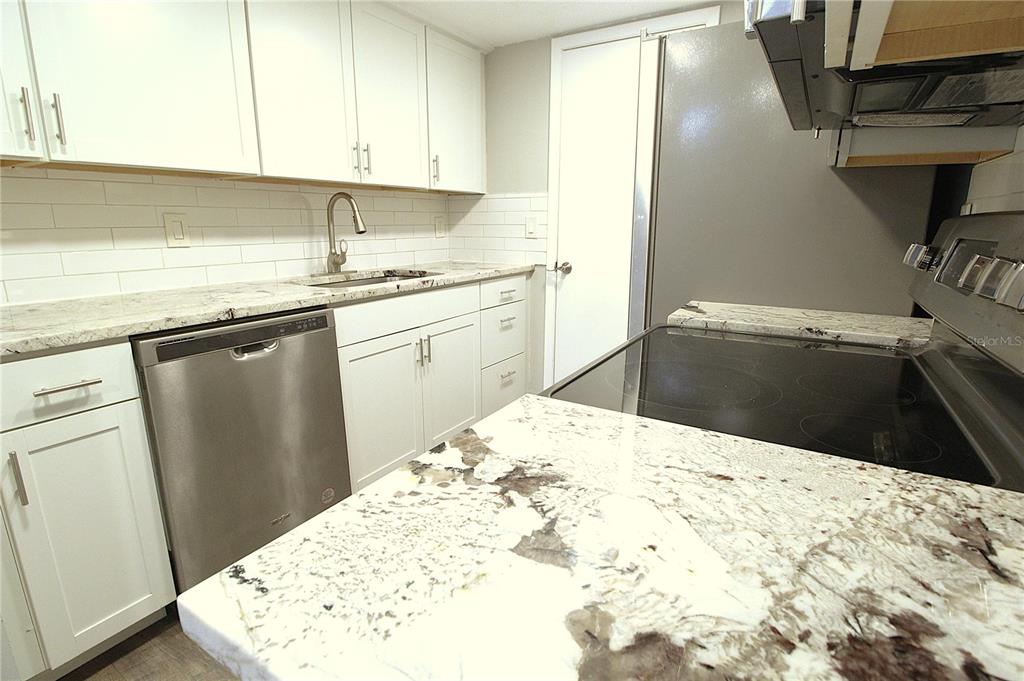 A kitchen features white cabinets, granite countertops, a stainless steel dishwasher, and a subway tile backsplash — 4119 61ST AVENUE TERRACE W UNIT 407, BRADENTON, FL