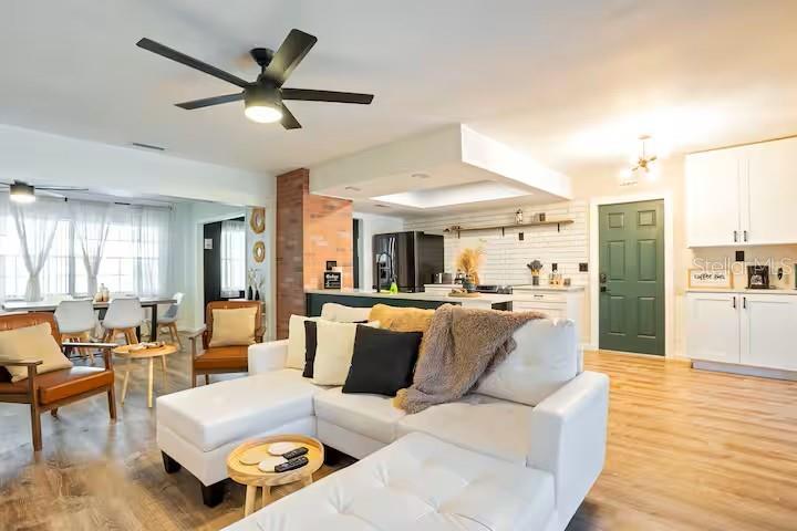 An open-concept living room and kitchen feature a white sectional sofa, wood flooring, and cabinetry — 146 LAKE RING DRIVE, WINTER HAVEN, FL