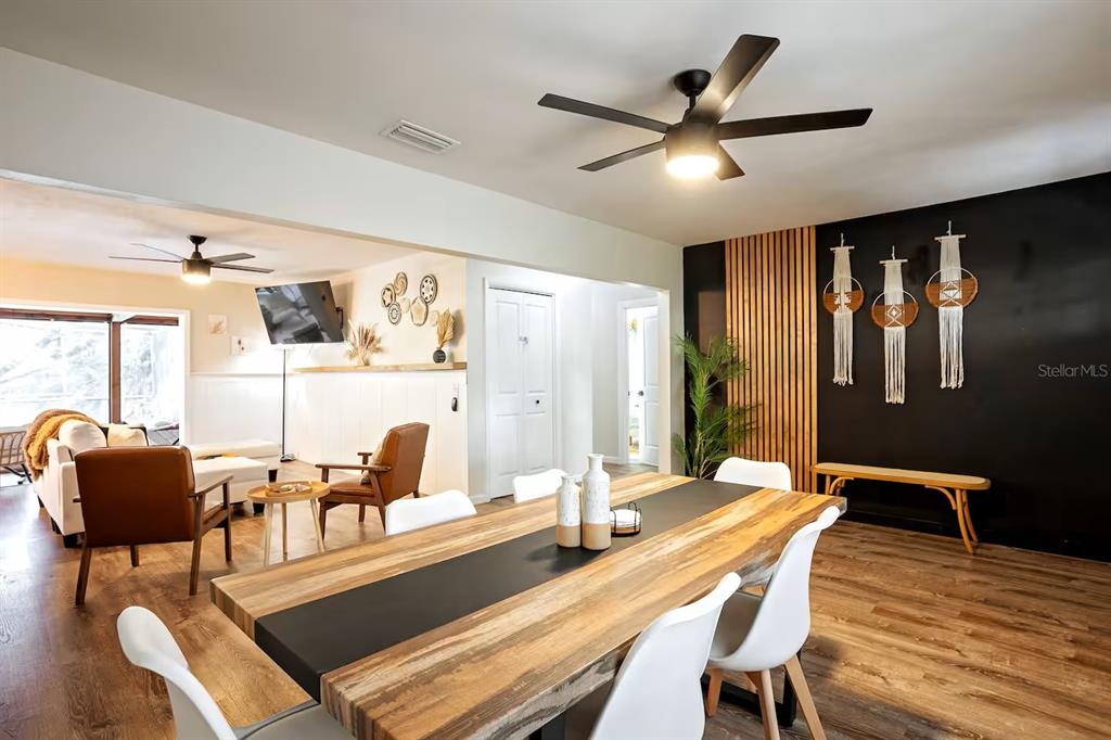 A dining room with a wood-topped table, black accent wall, and adjacent living area — 146 LAKE RING DRIVE, WINTER HAVEN, FL
