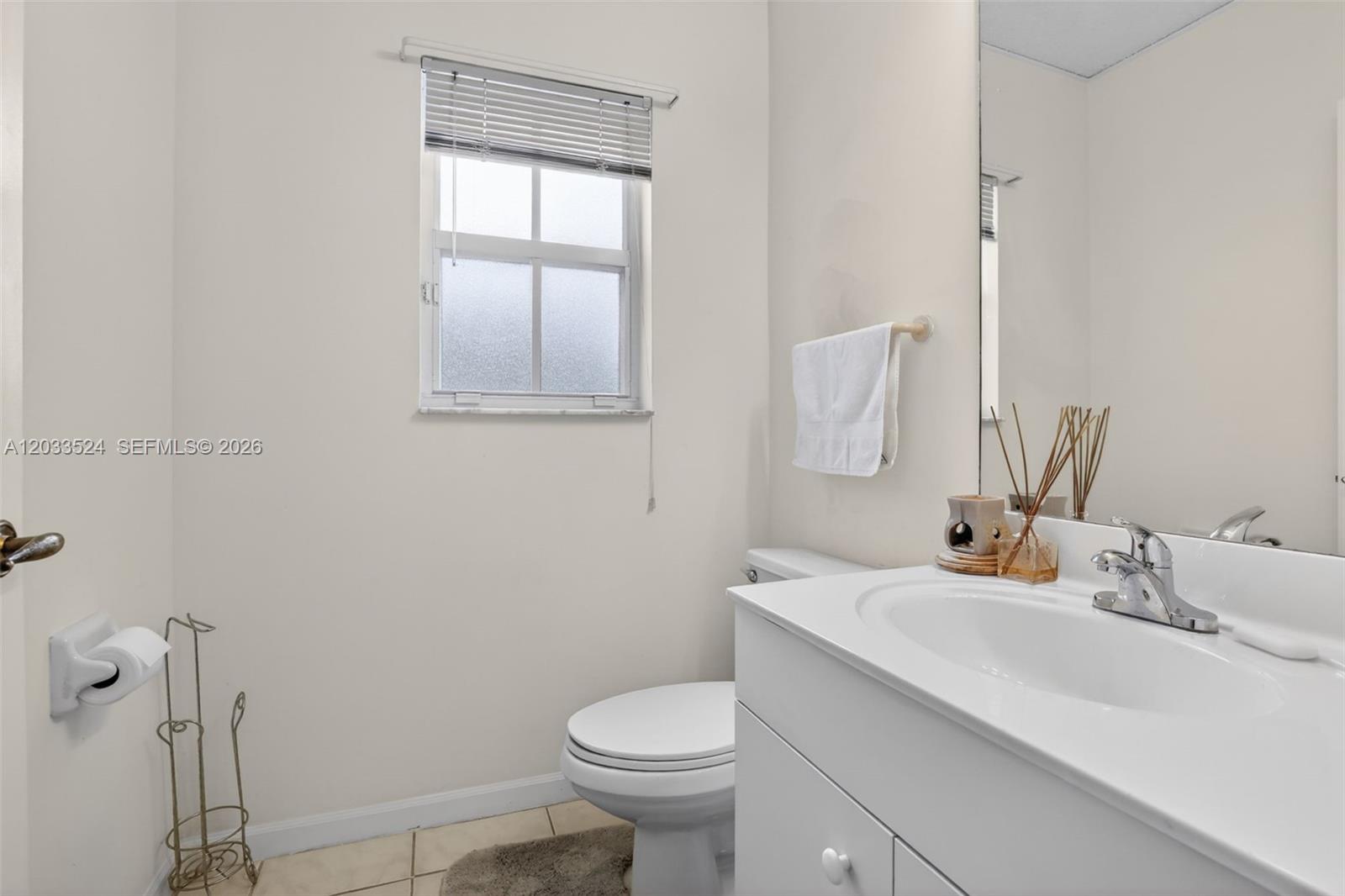 A bathroom features a white vanity, a toilet, a window with blinds, and a mirror — PEMBROKE PINES, FL