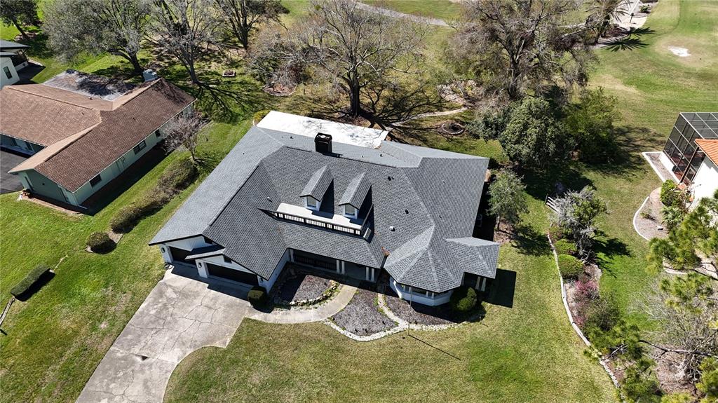 An aerial view shows a single-story house with a gray shingled roof and dormer windows — 5331 SADDLEBROOK WAY, WESLEY CHAPEL, FL