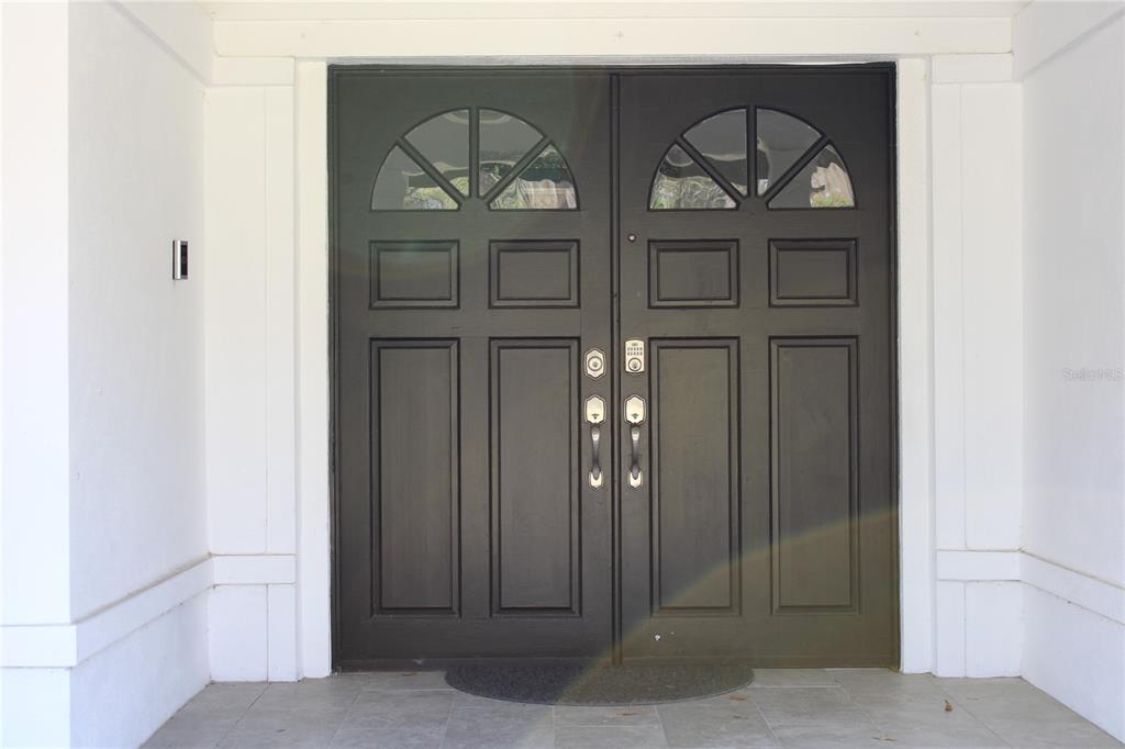 A pair of dark double doors with arched glass panels set in a white entryway — 5331 SADDLEBROOK WAY, WESLEY CHAPEL, FL