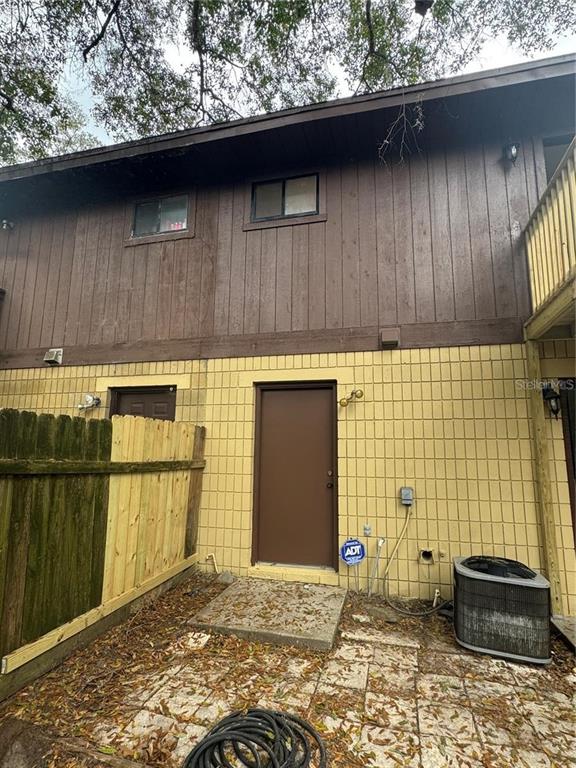 The exterior of a two-story building features brown wood siding, yellow brick, and a patio — 4313 SW 68 TERRACE, GAINESVILLE, FL