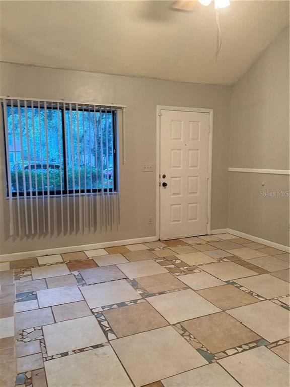 A room with light-colored walls, a white door, a window with vertical blinds, and tiled flooring — 4313 SW 68 TERRACE, GAINESVILLE, FL