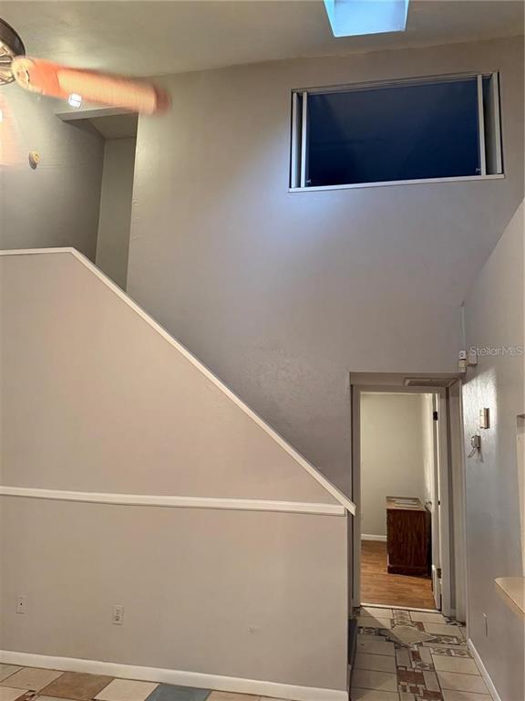 A high-ceilinged room features a staircase, a rectangular upper window, and a doorway leading inside — 4313 SW 68 TERRACE, GAINESVILLE, FL