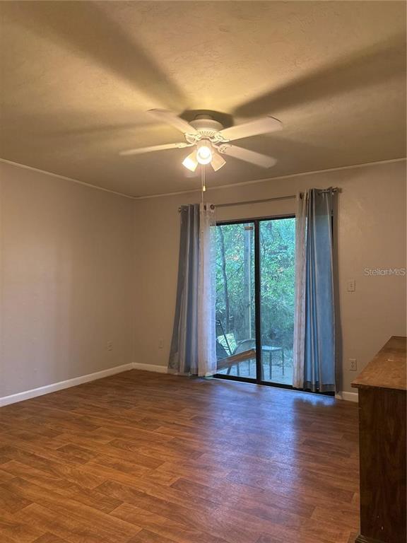 A room with wood-look flooring, a ceiling fan, and sliding glass doors leading outside — 4313 SW 68 TERRACE, GAINESVILLE, FL