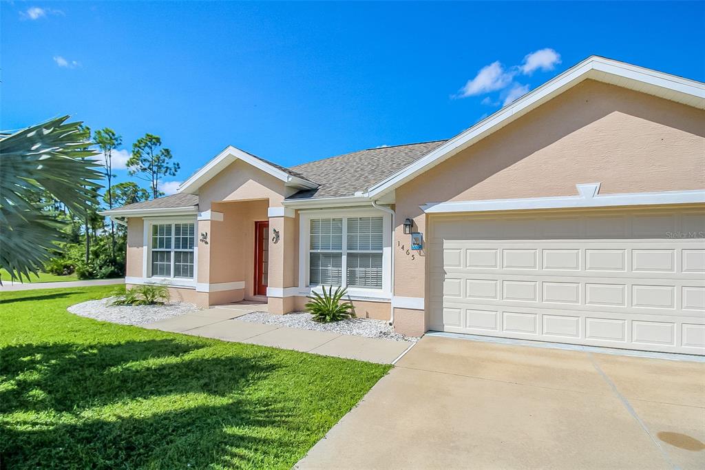 A single-story house with a beige stucco exterior, a two-car garage, and a red front door — 1465 SHIELDS STREET, PUNTA GORDA, FL