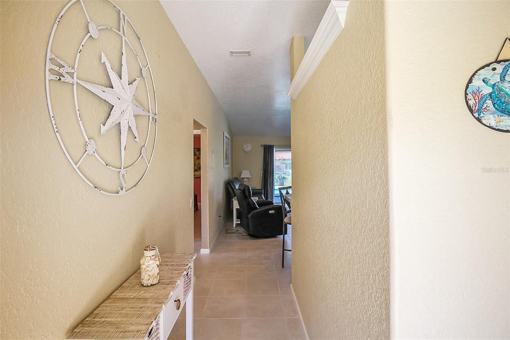 A hallway with beige walls, tile floors, a compass wall decoration, and a console table — 1465 SHIELDS STREET, PUNTA GORDA, FL