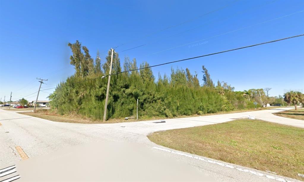 A vacant, tree-covered corner lot sits at the intersection of two paved roads — 101 GLENHOLM AVENUE, PUNTA GORDA, FL