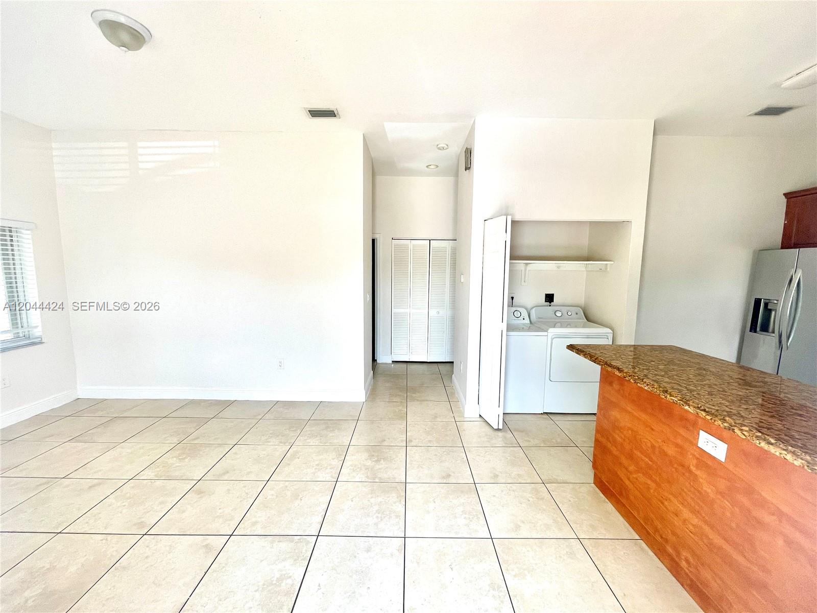 A room with tile flooring, a laundry closet, and a kitchen island with granite countertops — 2487 W 5th Ct, Hialeah FL 33010, HIALEAH, FL