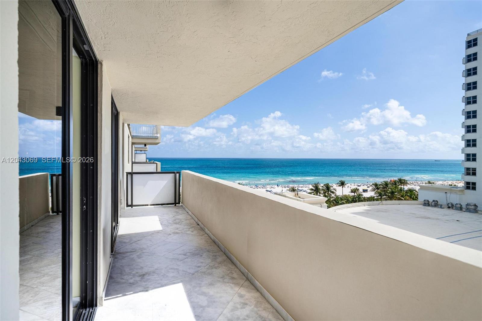 A balcony with tile flooring overlooks a beach, ocean, and a neighboring high-rise building — 1623 Collins Ave, Miami Beach FL 33139, MIAMI BEACH, FL