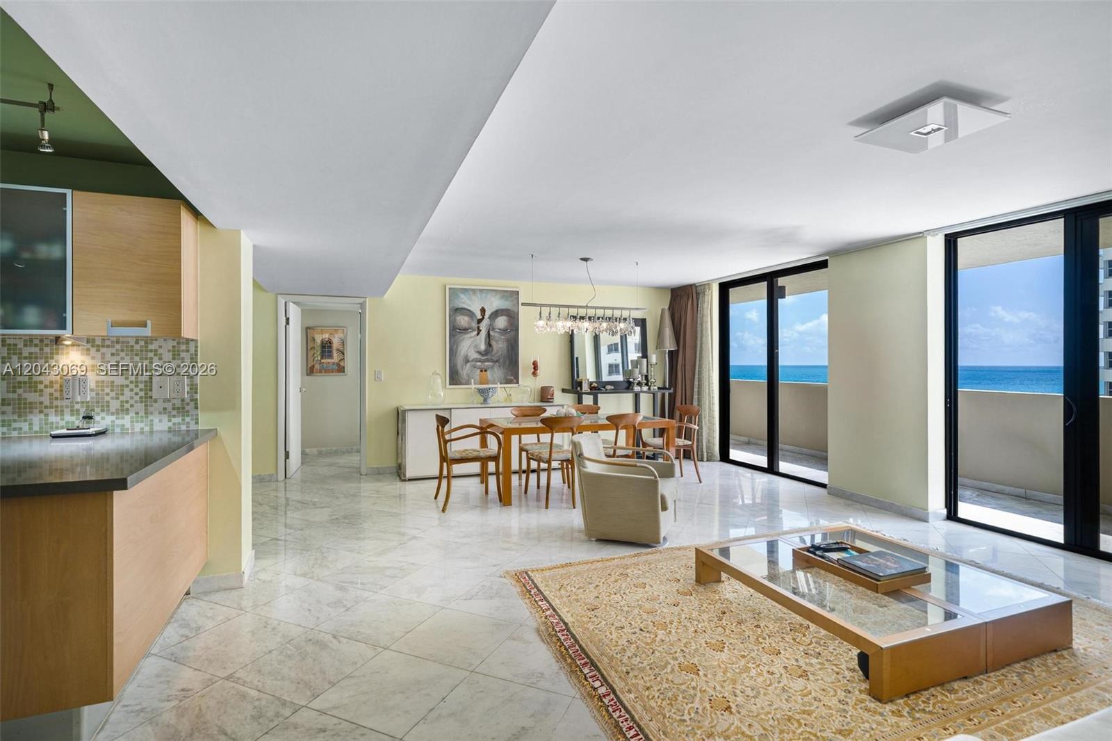 An open-concept living and dining area features marble floors, light wood cabinets, and ocean views — 1623 Collins Ave, Miami Beach FL 33139, MIAMI BEACH, FL