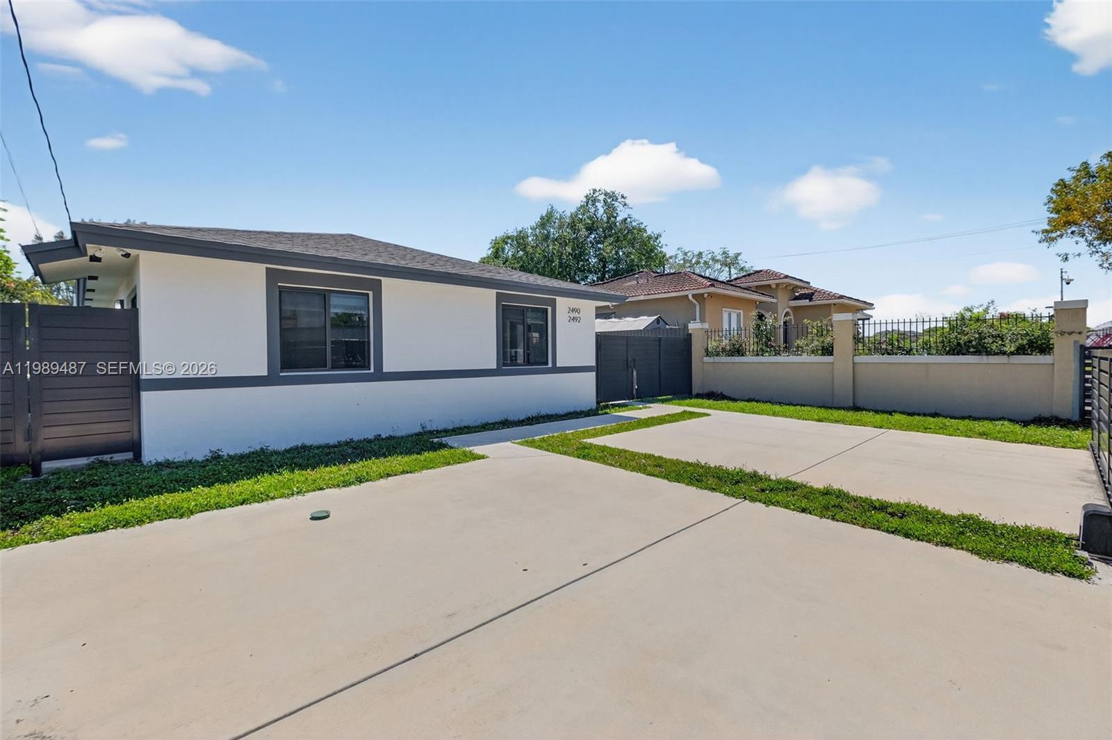 A white single-story house with a gray trim and a concrete driveway under a blue sky — 2490 NW 44th St # 2490, Miami FL 33142, MIAMI, FL