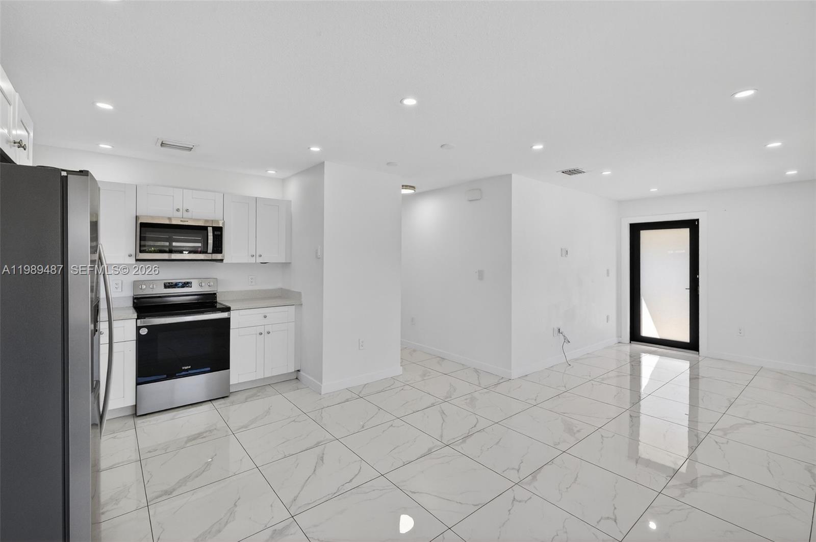 A modern kitchen with white cabinets, stainless steel appliances, and white marble-patterned tile flooring — 2490 NW 44th St # 2490, Miami FL 33142, MIAMI, FL