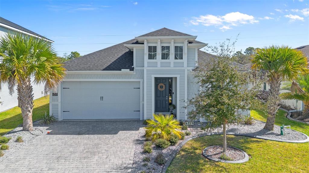 A single-story house with a gray garage, light siding, and palm trees in the yard — 6219 WOODHAVEN VILLAGE DRIVE, PORT ORANGE, FL