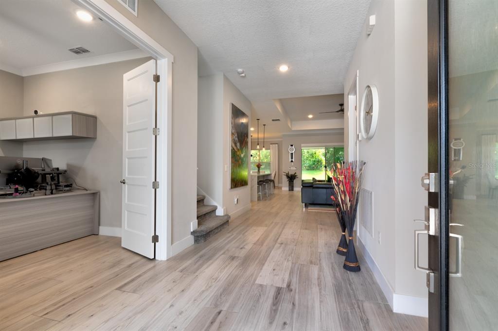 A bright entryway with light wood flooring leads to a home office and open living area — 25962 HIGH HAMPTON CIRCLE, SORRENTO, FL