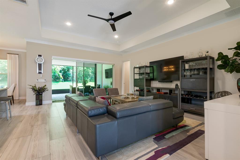 A living room features a grey sectional sofa, a television, and sliding glass doors to a patio — 25962 HIGH HAMPTON CIRCLE, SORRENTO, FL