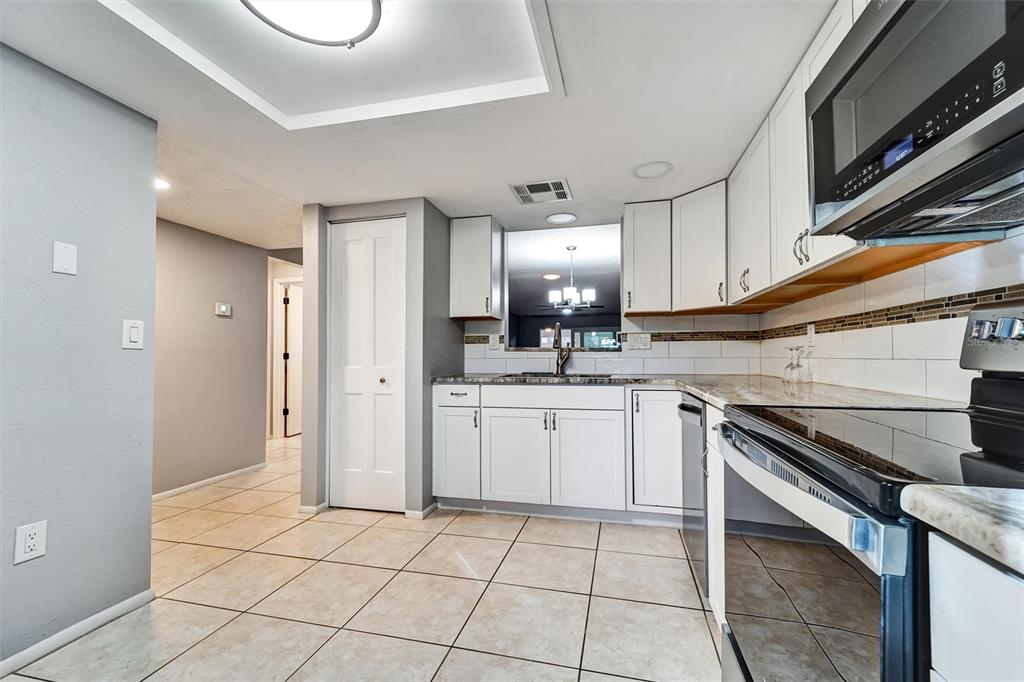 A kitchen features white cabinets, tile flooring, a microwave, and a pass-through window — 8330 HIGH POINT CIRCLE UNIT 6, PORT RICHEY, FL