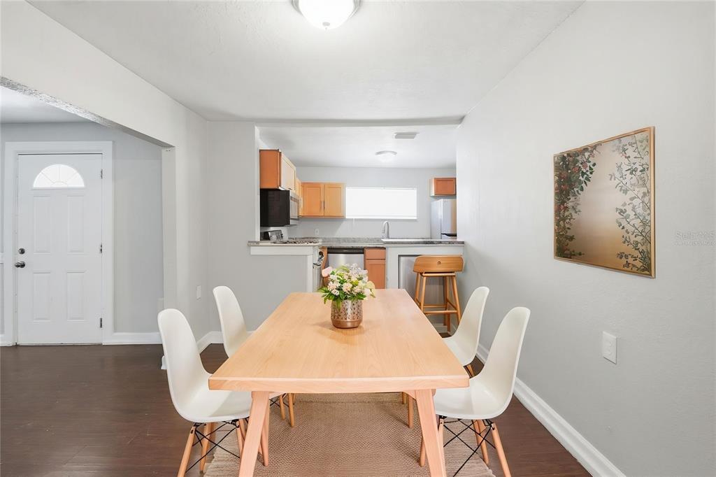 A dining area with a wooden table, four white chairs, and an adjacent kitchen — 1410 E WATERS AVENUE, TAMPA, FL