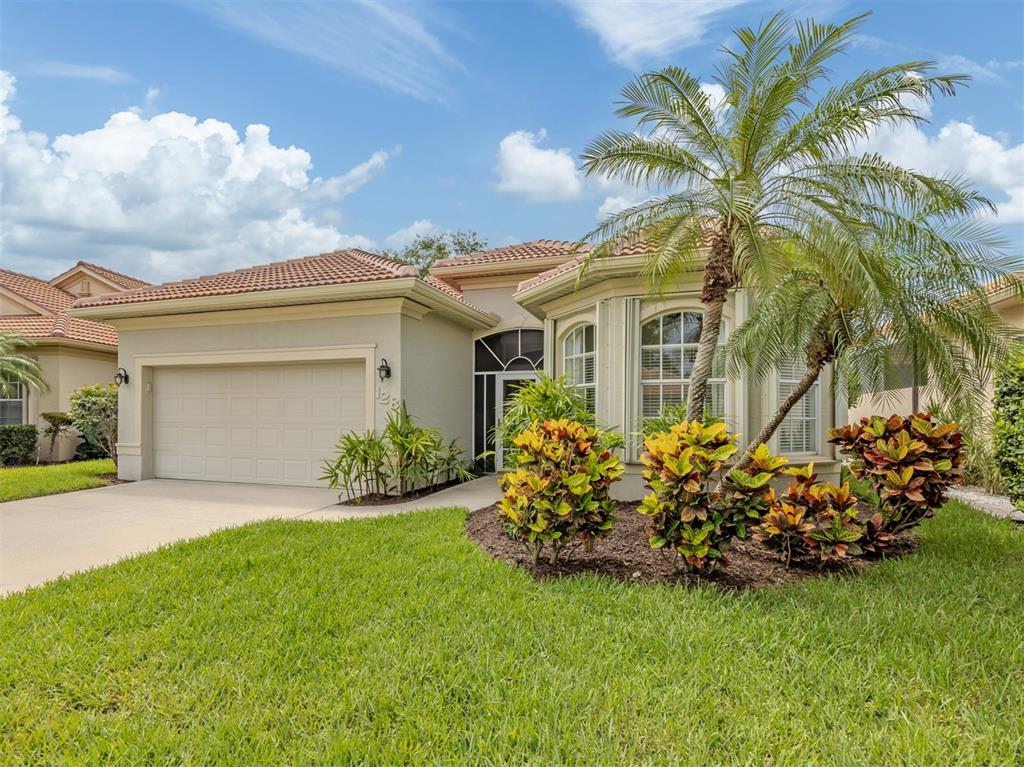 A single-story house with a beige stucco exterior, a two-car garage, and a palm tree — 128 AMORA AVENUE, VENICE, FL
