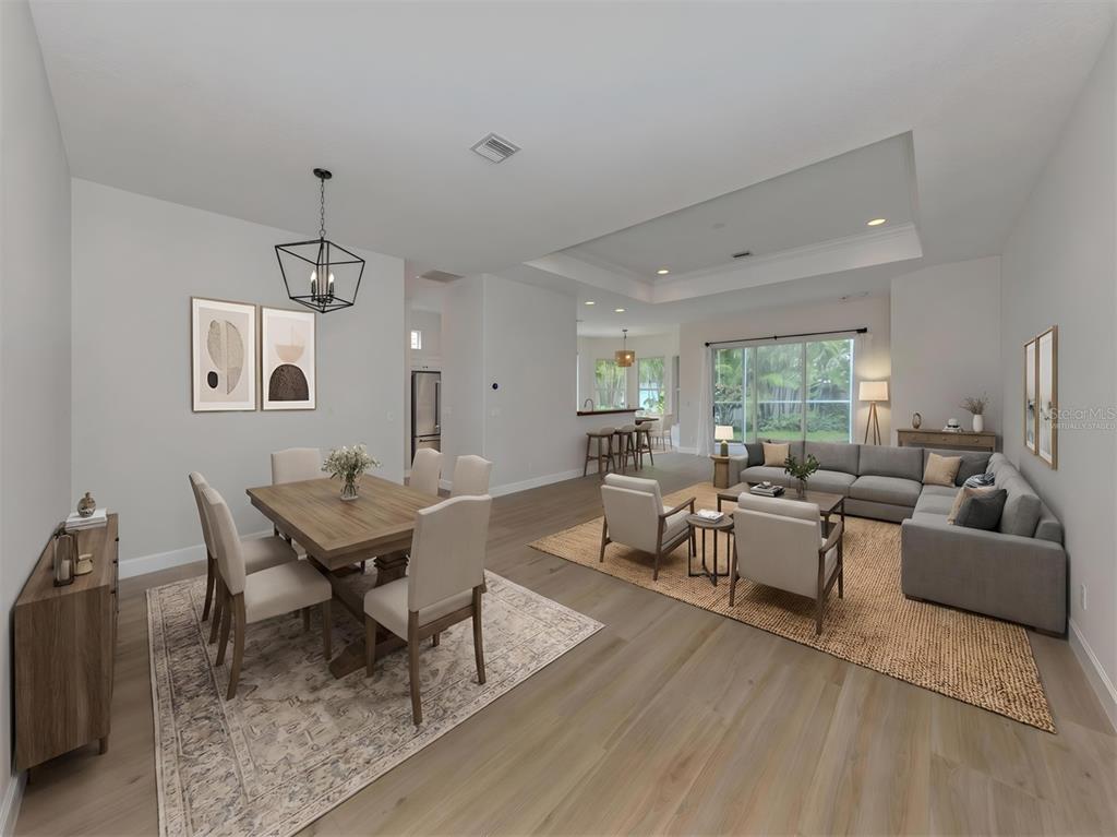 An open-concept living and dining room with light wood floors and neutral furniture — 128 AMORA AVENUE, VENICE, FL