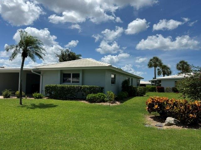 A light green single-story house with a tiled roof sits on a grassy lawn — 7011 9TH AVENUE W, BRADENTON, FL