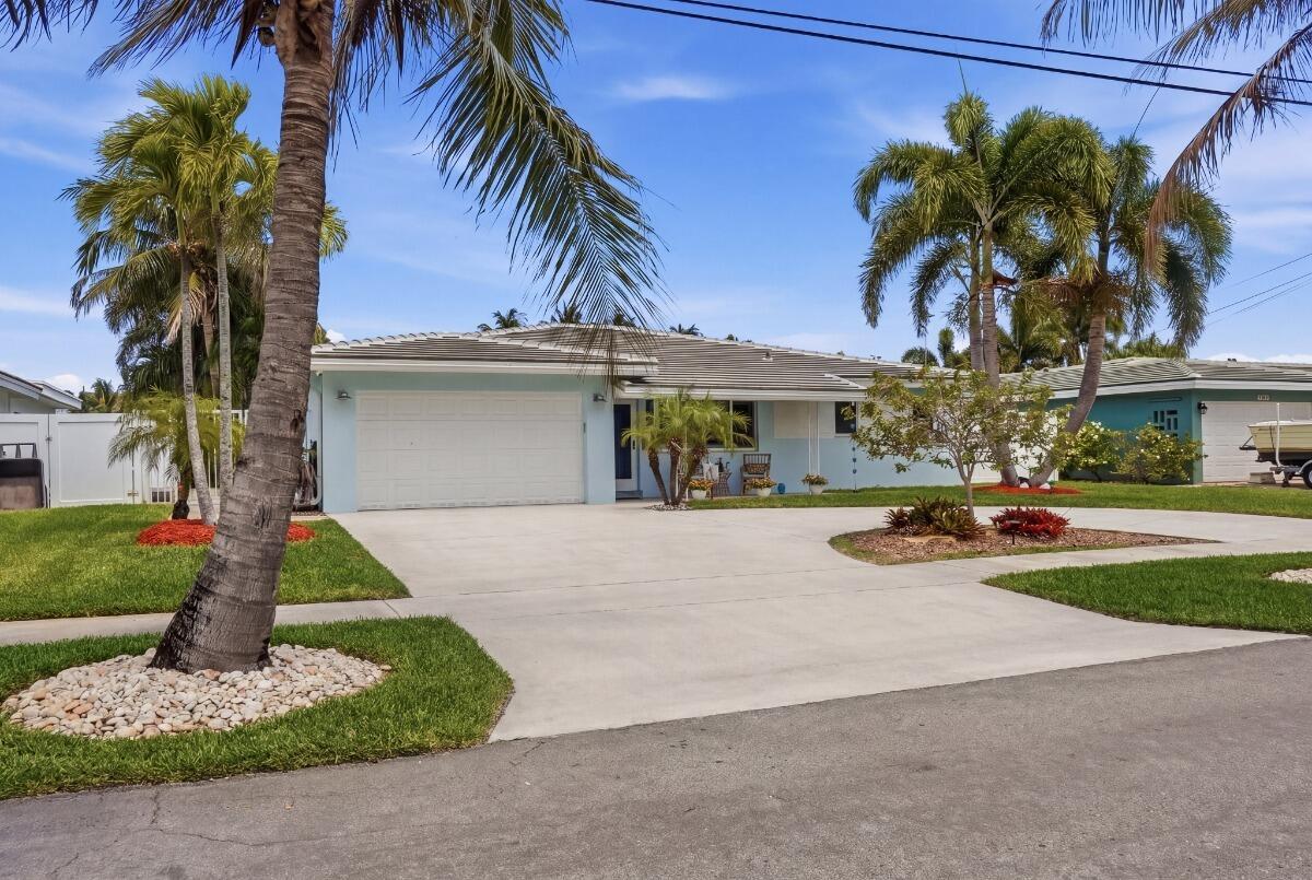 A light blue single-story house with a concrete driveway and palm trees in the yard — 380 SE 5th Avenue, Pompano Beach FL 33060, POMPANO BEACH, FL