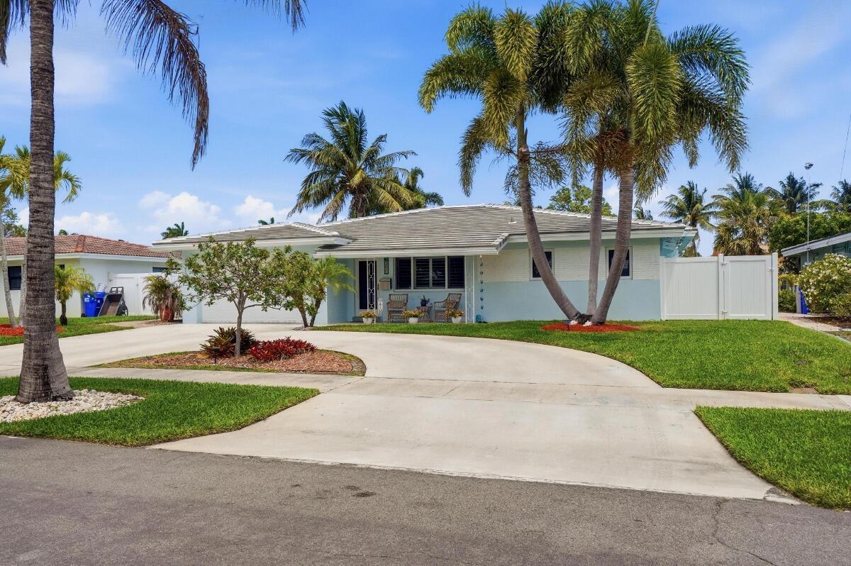 A light blue single-story house with a concrete driveway and palm trees in the front — 380 SE 5th Avenue, Pompano Beach FL 33060, POMPANO BEACH, FL