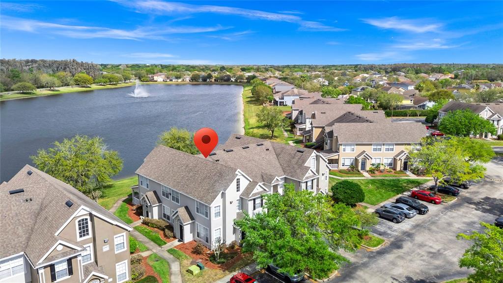 An aerial view shows a multi-story apartment building situated next to a lake — 9013 LEE VISTA BOULEVARD UNIT 1910, ORLANDO, FL