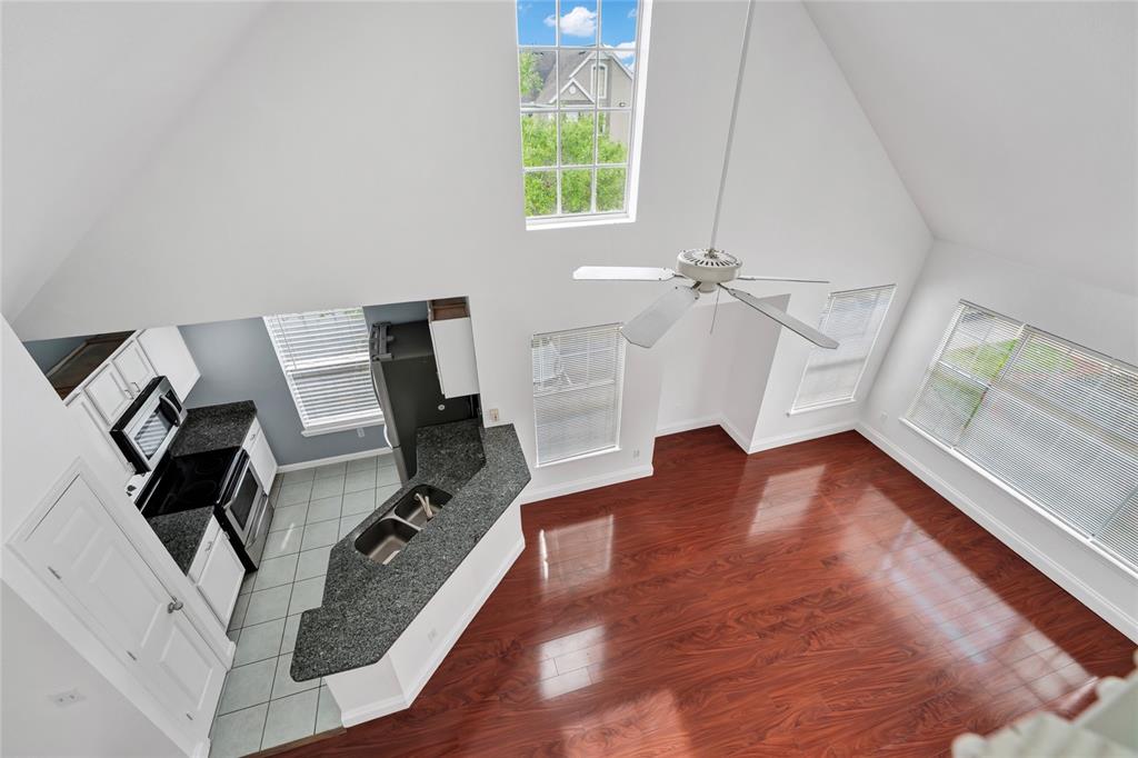 An elevated view of a kitchen with granite counters and a living area with hardwood floors — 9013 LEE VISTA BOULEVARD UNIT 1910, ORLANDO, FL