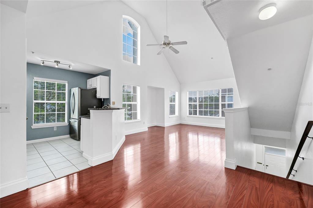 An open-concept living area features vaulted ceilings, hardwood floors, and an adjacent tiled kitchen — 9013 LEE VISTA BOULEVARD UNIT 1910, ORLANDO, FL
