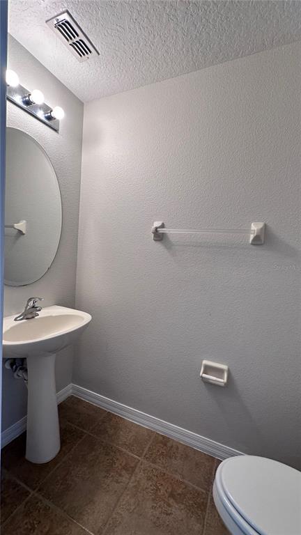 A small bathroom features a pedestal sink, oval mirror, towel bar, and tile flooring — 517 INTERLUDE LANE UNIT H-105, ORLANDO, FL