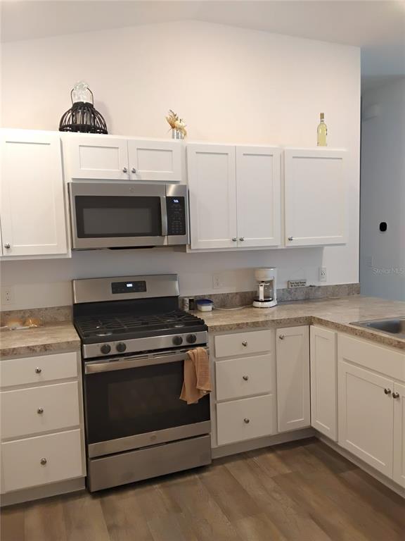 A kitchen features white cabinets, stainless steel appliances, and tan laminate countertops — 3561 COCHRAN STREET, THE VILLAGES, FL