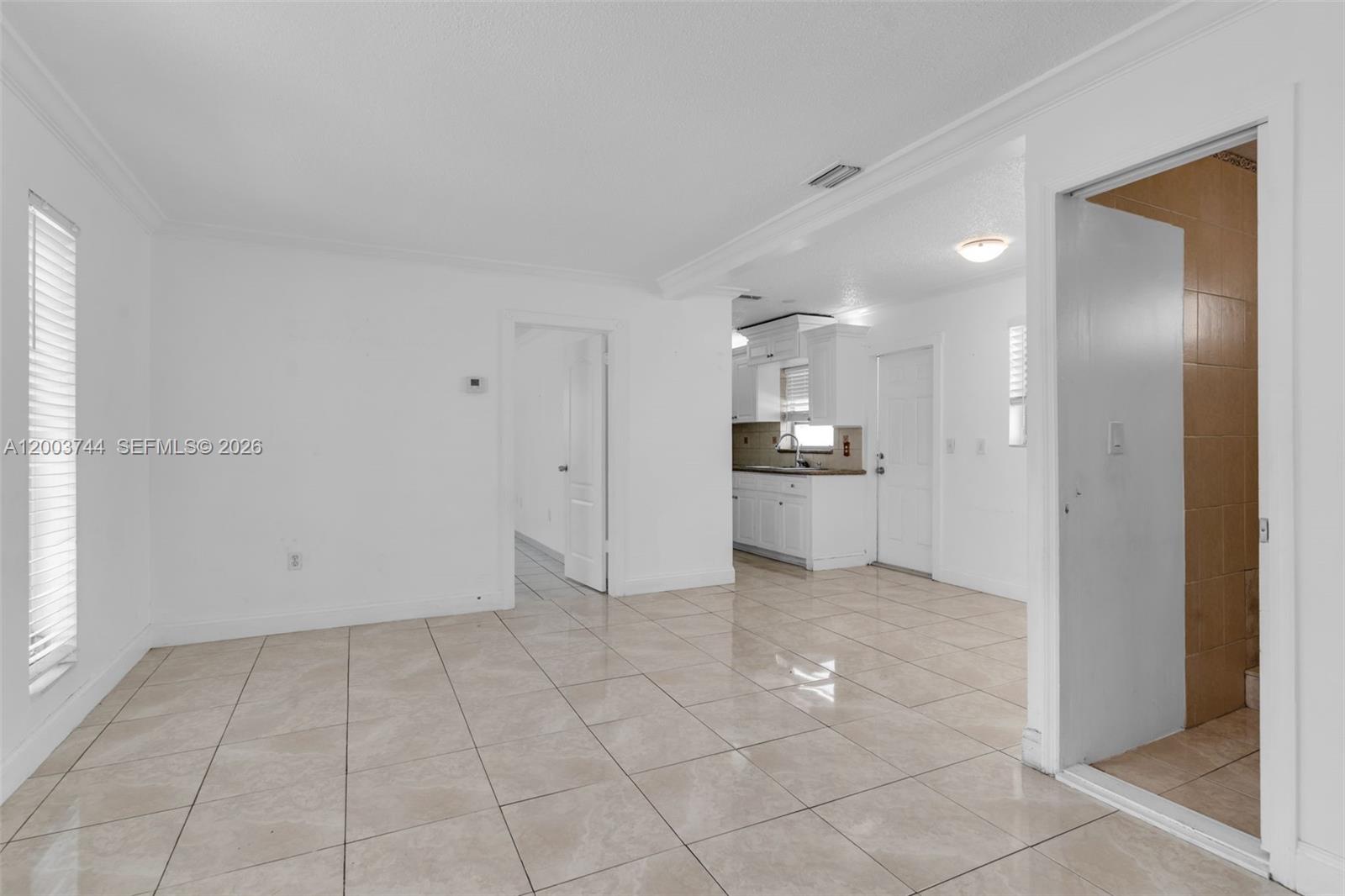 A bright room with light-colored tile flooring leads to a kitchen and a tiled bathroom — 1101 SW 17th Ave # 0, Miami FL 33135, MIAMI, FL