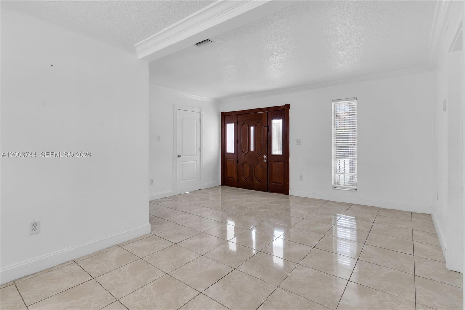An entryway features light-colored tile flooring, white walls, a wooden front door, and a window — 1101 SW 17th Ave # 0, Miami FL 33135, MIAMI, FL