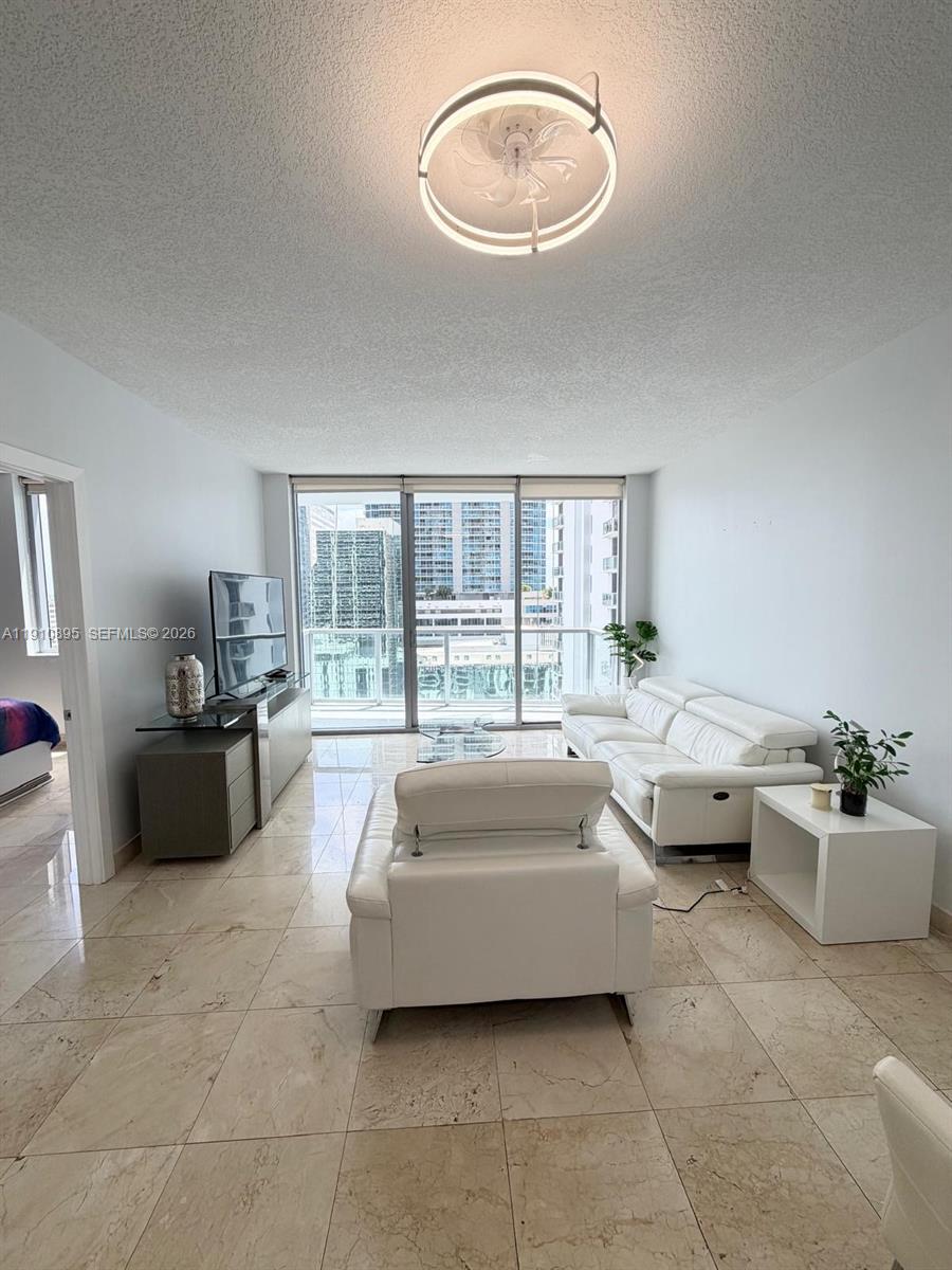 A living room features white leather furniture, tile flooring, and a balcony with city views — 1050 Brickell Ave # 1904, Miami FL 33131, MIAMI, FL