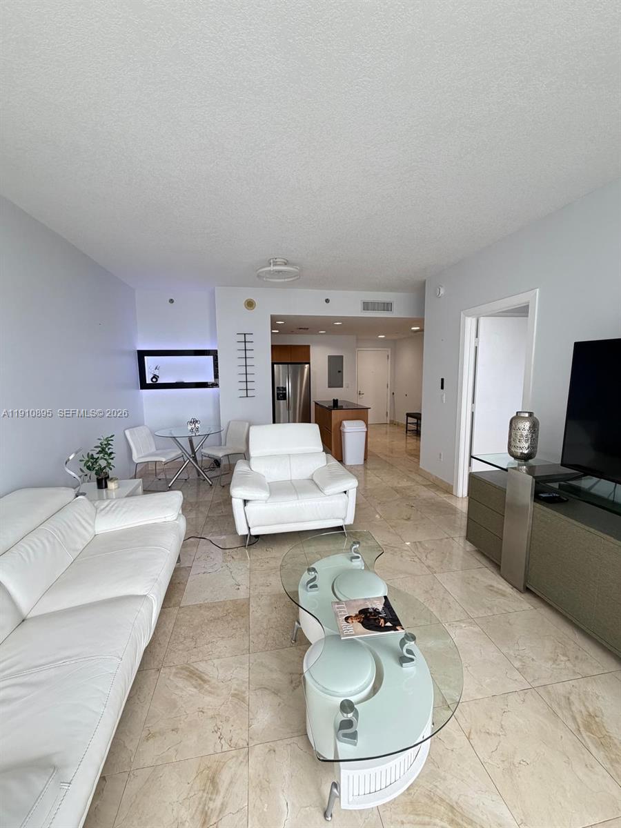 A living room features white leather furniture, a glass coffee table, and beige tile flooring — 1050 Brickell Ave # 1904, Miami FL 33131, MIAMI, FL