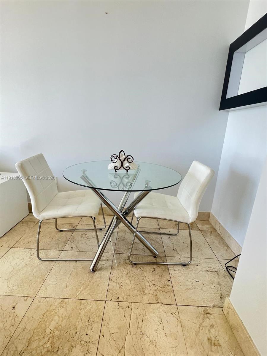 A small dining area features a glass-topped table, two white chairs, and tiled flooring — 1050 Brickell Ave # 1904, Miami FL 33131, MIAMI, FL