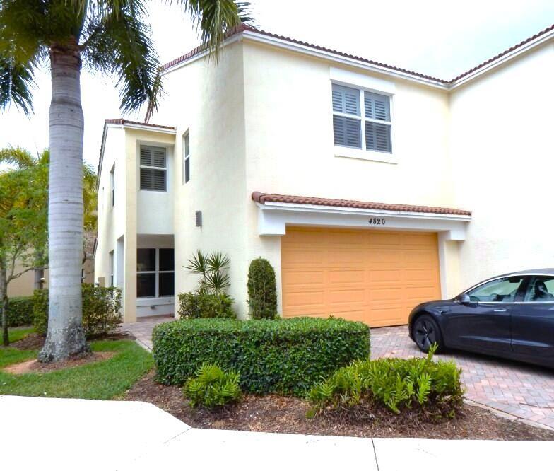 A two-story stucco townhouse features a tan garage, a palm tree, and a parked car — 4820 NW 16th Terrace, Boca Raton FL 33431, BOCA RATON, FL