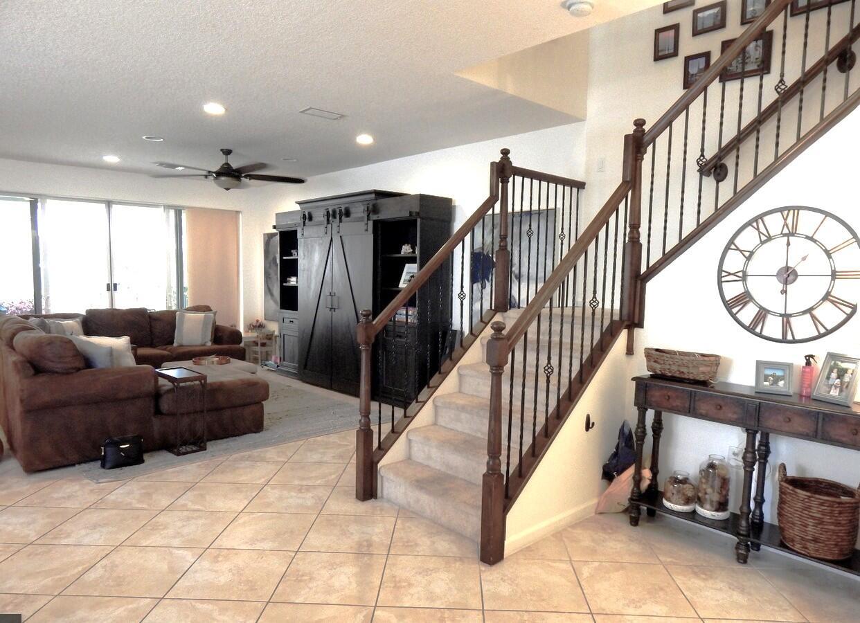 A living room with a brown sectional, tile flooring, and a staircase with wooden railings — 4820 NW 16th Terrace, Boca Raton FL 33431, BOCA RATON, FL