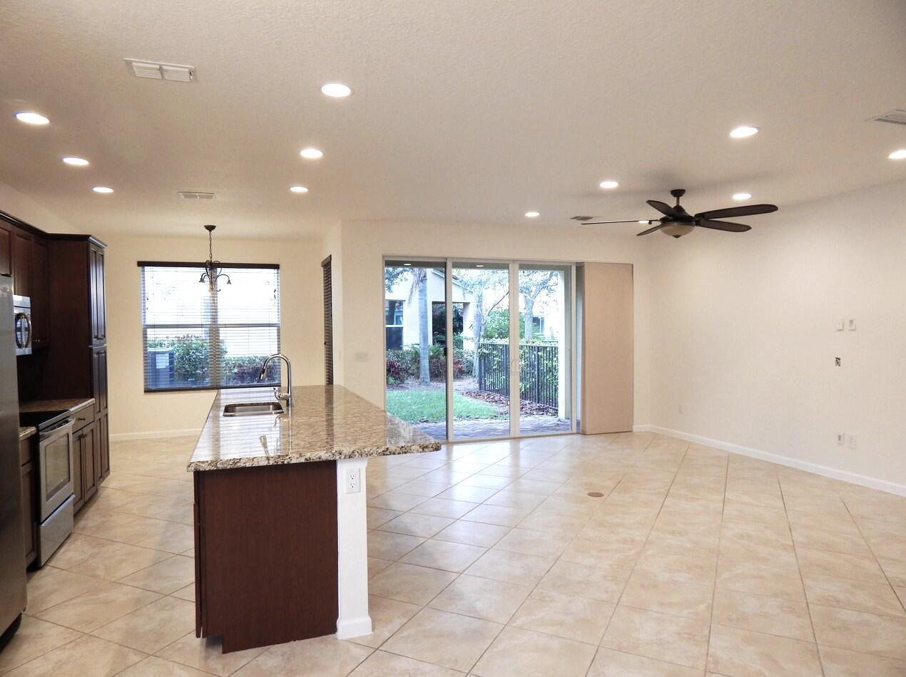 A kitchen with dark cabinets, granite countertops, and an island opens to a tiled living area — 4820 NW 16th Terrace, Boca Raton FL 33431, BOCA RATON, FL